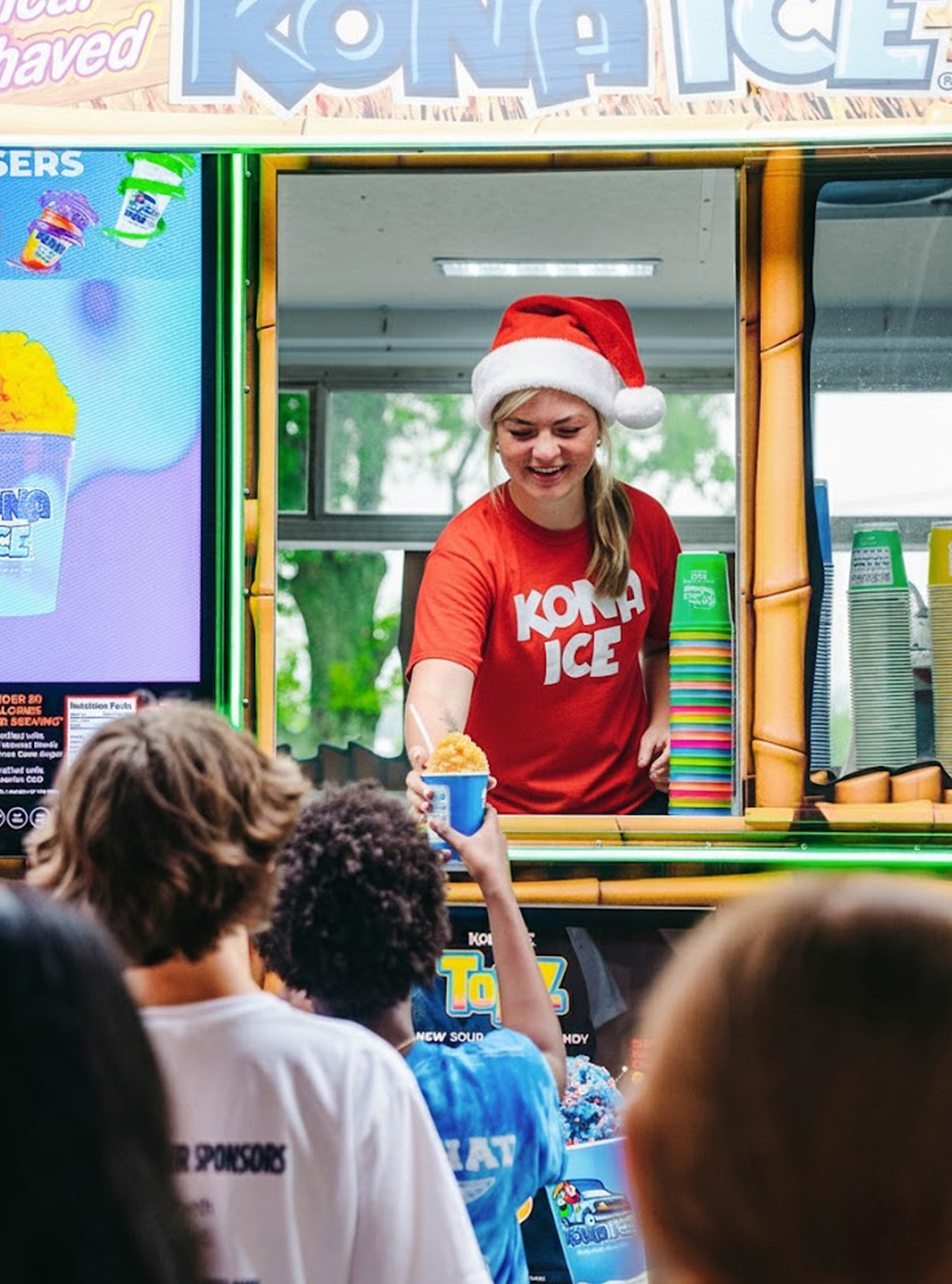 A group of students waits in line at a Kona Ice truck for a school event