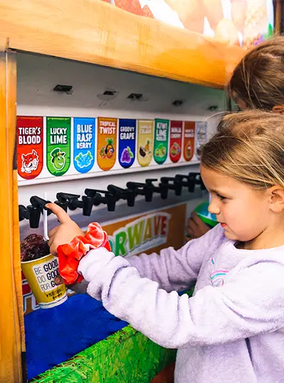 A young customer uses the Flavorwave machine to fill up her Kona Ice cup with the Tiger’s Blood flavor.