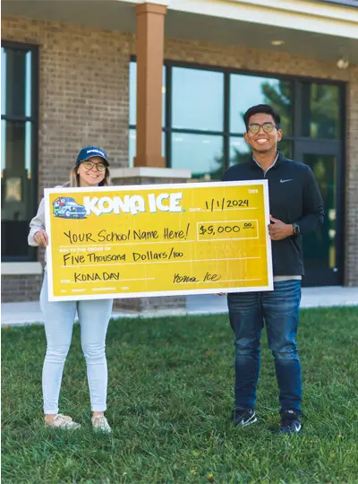 Two people smiling while holding a giant Kona Ice giveback check